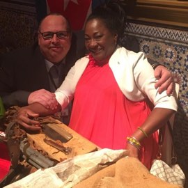 Besucher nimmt Zigarrenrollerin nach der Vorstellung für Foto in den Arm