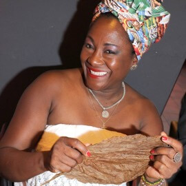 Foto von Alicia der kubanischen Zigarrenrollerin mit einem getrockneten Tabakblatt