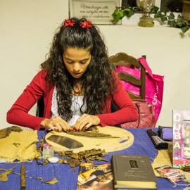 Zigarrenrollerin am Tisch beim Rollen einer neuen Zigarre