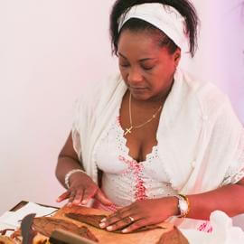 Ein Zigarrenrollerin streicht ein Tabakblatt auf dem Arbeitstisch glatt