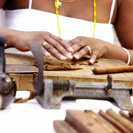 Foto vom Arbeitstisch einer zigarrenrollerin bei der Arbeit, mit einer schon fast ferigen Zigarre