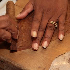 Ein Tabakblatt wird auf die Zigarre gewickelt