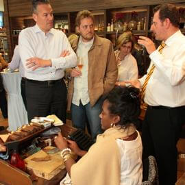 Ein Zigarren-Connaisseure erklärt besuchern wie die Zigarredreherin am Tisch arbeitet