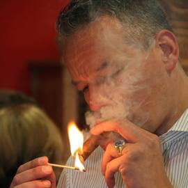 Ein Geniesser steckt sich eine Zigarre mit dem Streichholz an